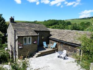 uma casa de tijolos com duas cadeiras e uma mesa em Wood End Cottage em Slaithwaite