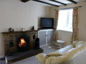 a living room with a fireplace and a tv at Wood End Cottage in Slaithwaite