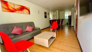 ein Wohnzimmer mit einem Sofa und roten Stühlen in der Unterkunft Av santander apartamento perfecta ubicación in Manizales