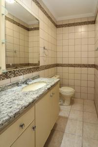 y baño con lavabo, aseo y espejo. en Maravilhoso apartamento vista para o mar - AI01I, en Florianópolis