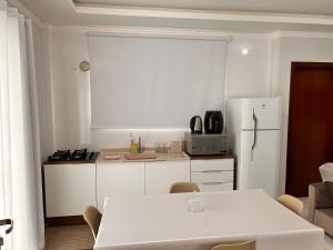 uma cozinha com uma mesa branca e um frigorífico branco em Apto térreo com garagem coberta em Tijucas