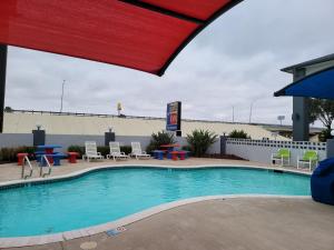 a pool at a hotel with tables and chairs at Texas Inn and Suites Raymondville in Raymondville