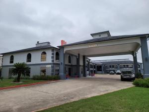 a large building with a parking lot with a bus at Texas Inn and Suites Raymondville in Raymondville