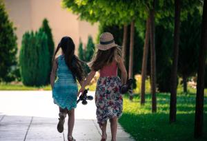 two young girls walking down a sidewalk holding a skateboard at Apart Hotel Apolonia Palace in Sinemorets