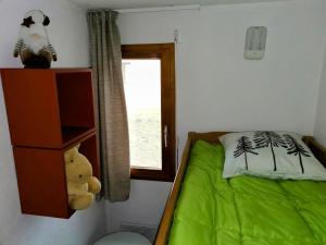 a small bedroom with a green bed and a window at Appartement "ENTOURLOUP" classé 2 étoiles in Le Dévoluy