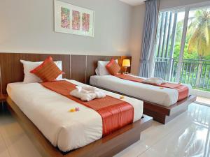 two beds in a room with a window at Ahad Suite Aonang in Ban Khlong Haeng