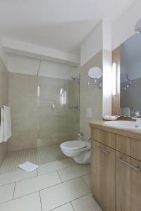 a bathroom with a toilet and a shower and a sink at Michels Hanseatic Hotel Norderney in Norderney