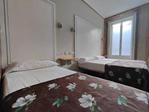 una camera d'albergo con due letti e una finestra di Hostal Madrid a Madrid