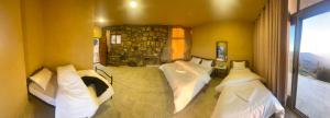 a bedroom with white beds and a stone wall at Wild Dana Eco Lodge- Hotel-Eco-Camp in Dana