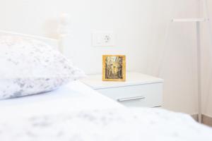 a white bedroom with a bed with a picture on it at Apartments Luka in Senj