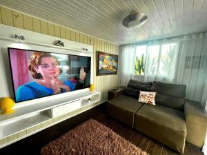 a living room with a couch and a flat screen tv at Espetacular! Casa em com vista deslumbrante in Governador Celso Ramos