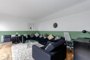 - un salon avec un canapé noir et des chaises dans l'établissement Cosy 1bedroom Flat - 2 Min Walk to Kensington Gardens!, à Londres