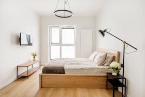 biała sypialnia z łóżkiem i oknem w obiekcie Chaplin Apartment w Poznaniu