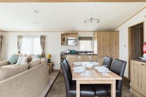 a living room with a table and a couch at Waters Edge, Hoburne Cotswolds in South Cerney