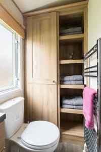 a bathroom with a toilet and some towels at Waters Edge, Hoburne Cotswolds in South Cerney