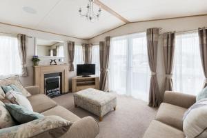 a living room with a couch and a tv at Waters Edge, Hoburne Cotswolds in South Cerney