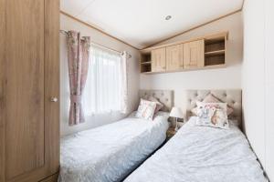two beds in a small bedroom with a window at Waters Edge, Hoburne Cotswolds in South Cerney +48 photos