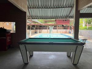 a pool table in front of a swimming pool at Pesque pague pousada do Carlinho in Pinheiral