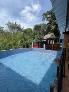 uma grande piscina azul com um gazebo em Pesque pague pousada do Carlinho em Pinheiral