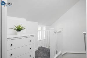 a white bedroom with a dresser and a staircase at Bright 2bed Apartment in Worksop in Worksop