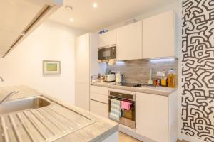 a kitchen with white cabinets and a sink at Stunning 1bedroom Flat wBalcony - Surrey Quays! in London