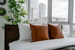 a bed with white and brown pillows in front of a window at The Perfect Getaway in Toronto