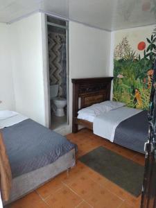 a bedroom with two beds and a bathroom with a toilet at Hostal Chorro De Quevedo in Bogotá