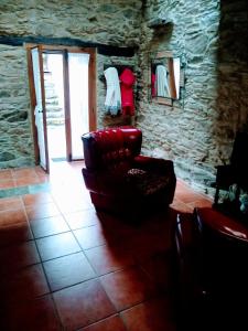 a living room with a red chair and a stone wall at Casa Pacios by M de Santiago in Treacastela