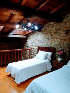 a bedroom with two beds and a stone wall at Casa Pacios by M de Santiago in Treacastela