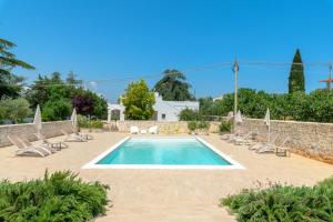 a swimming pool with lounge chairs and a villa at MandorloCarrubo's suite in Ostuni