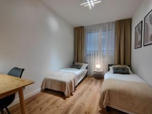 a room with two beds and a table and a window at ApartamentySnu, Bulwary II z parkingiem in Radom