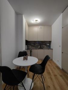 a dining room with a table and chairs and a kitchen at ApartamentySnu, Bulwary II z parkingiem in Radom