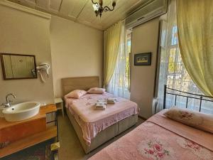 a bedroom with two beds and a sink and a window at Eolya Konuk Evi in Ayvalık