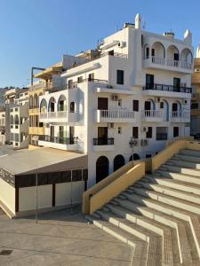 a large white building with stairs in front of it at P i g a d i a B a y in Karpathos Town