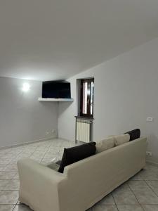 ein weißes Sofa im Wohnzimmer mit einem TV in der Unterkunft DR HOUSE in Airola