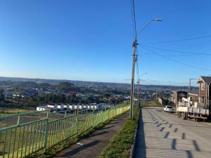 a road with a fence and a street light at Hermosa Casa en buen barrio residencial in Castro