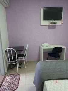 1 dormitorio con 2 sillas, escritorio y TV en Hotel Farrapos, en Porto Alegre