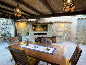 comedor al aire libre con mesa de madera y chimenea en Sandy Cove Patio Villa sul Mare, en Golfo Aranci