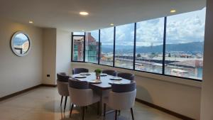 ein Esszimmer mit einem Tisch und Stühlen sowie einem großen Fenster in der Unterkunft 302 Departamento La Terraza in Cuenca