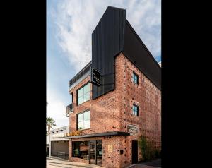 a tall brick building with a black roof at The Brick Boutique Hotel in Oceanside