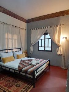 1 dormitorio con 1 cama con cortinas blancas y ventana en Riad dar idsalah, en Ouirgane