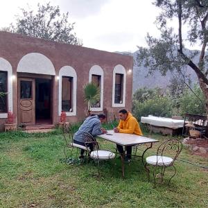 zwei Männer an einem Tisch vor einem Haus in der Unterkunft Riad dar idsalah in Ouirgane