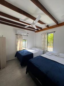 a bedroom with two beds and a ceiling fan at Cabaña Campestre con Piscina en la Hacienda Nápoles in Doradal