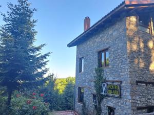 a sign on the side of a stone building with a tree at Lydia Lithos Mountain Resort in Metamorfosi