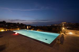 ein Schwimmbad in der Nacht mit einer Stadt im Hintergrund in der Unterkunft Lampetos Houses Molyvos in Mythimna
