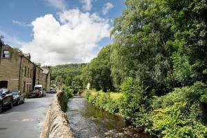 a river in a town with cars parked on the side of a street at Cambridge Mews - Central Hebden Bridge in Hebden Bridge