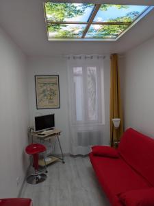 een woonkamer met een rode bank en een dakraam bij joli studio T2 meublé de 20 m² Située à 2 minutes à pied du MÉTRO in Marseille