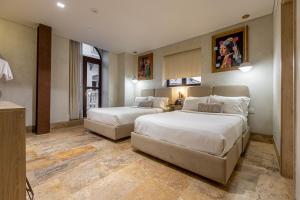 um quarto de hotel com duas camas e uma mesa em Voilá Centro Histórico em Cartagena de Indias
