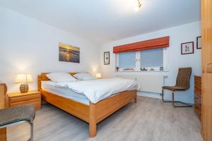 a bedroom with a bed and a chair and a window at Altstadttor 5 in Westerland