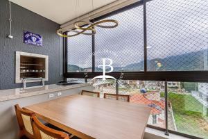 une cuisine avec une table en bois et une grande fenêtre dans l'établissement Um belo espaço Gourmet privativo e piscina exterior, à Governador Celso Ramos
